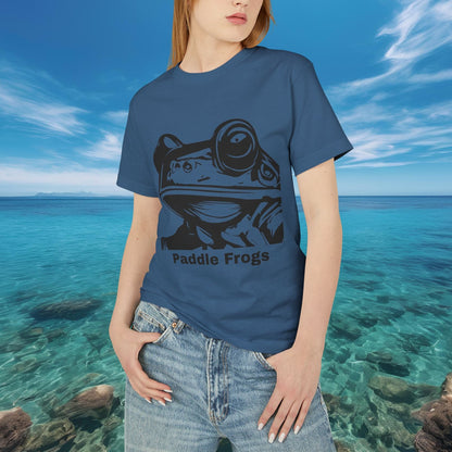 Person wearing a Faded Navy blue t-shirt with a frog graphic and 'Paddle Frogs' text, standing in front of a scenic ocean view.