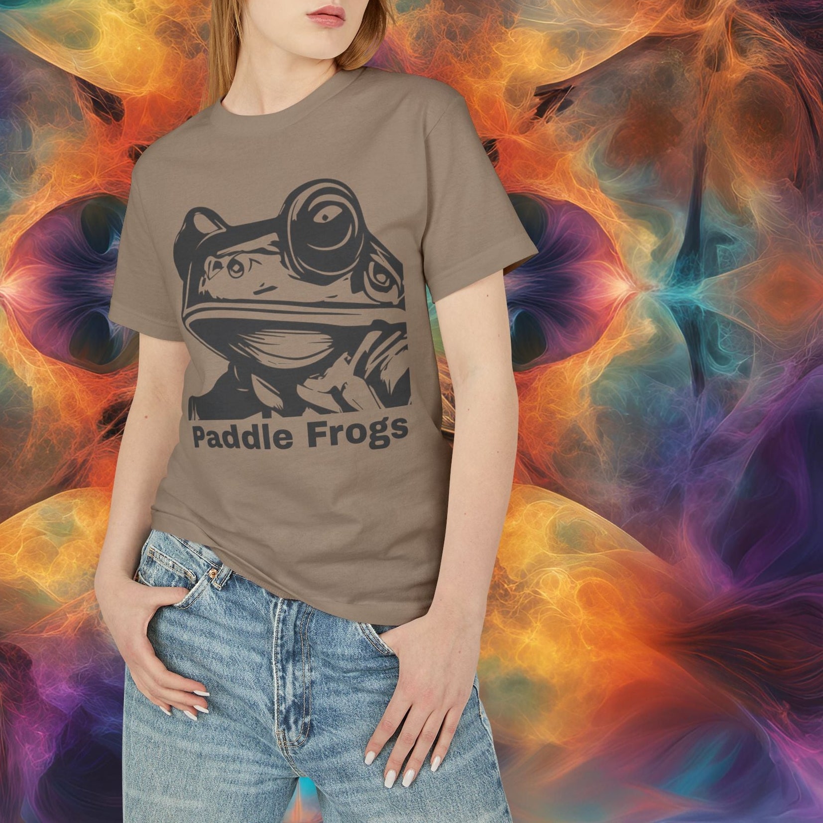 Person wearing a t-shirt with 'Paddle Frogs' design against a colorful abstract background Olive Chaos vs Sea Queen Faded Brown t-shirt with a colorful graphic on the back against a blue gradient background