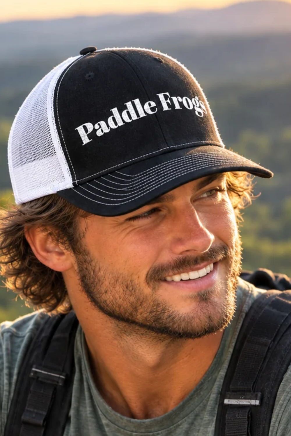 River Days Trucker Cap Paddle Frogs™ Embroidered hat a man climbing a mountain made for fishing kayaking paddleboarding hiking colors black with white mesh.
