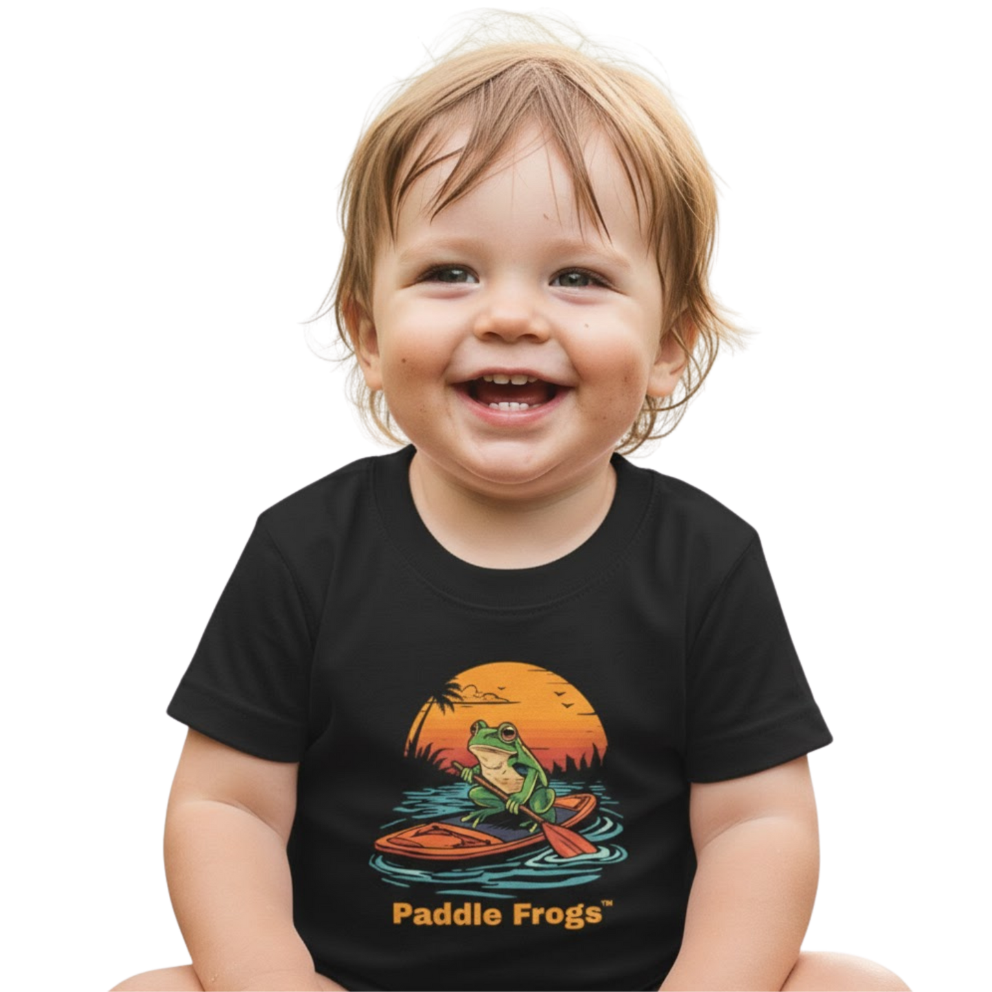 Sitting crisscross applesauce in the creek wearing the black Sunset Frog Paddle Board Explorer Toddler Tee "Skate & Paddle Frogs™ on a transparent background