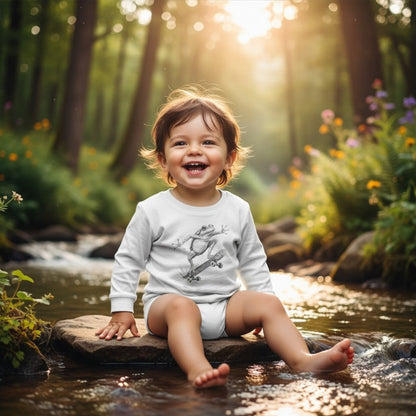 Child sitting on a rock by a stream in a forest with sunlight filtering through the trees. Sitting on a rock in the creek wearing White Skate Jam Long Sleeve Tee: Ollie Frog Kids Shirt | Paddle Frogs™