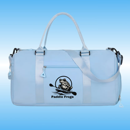 A light blue waterproof duffel bag with shiny blue handles and a black 'Paddle Frogs' frog logo printed on the front, set against a blue gradient background.