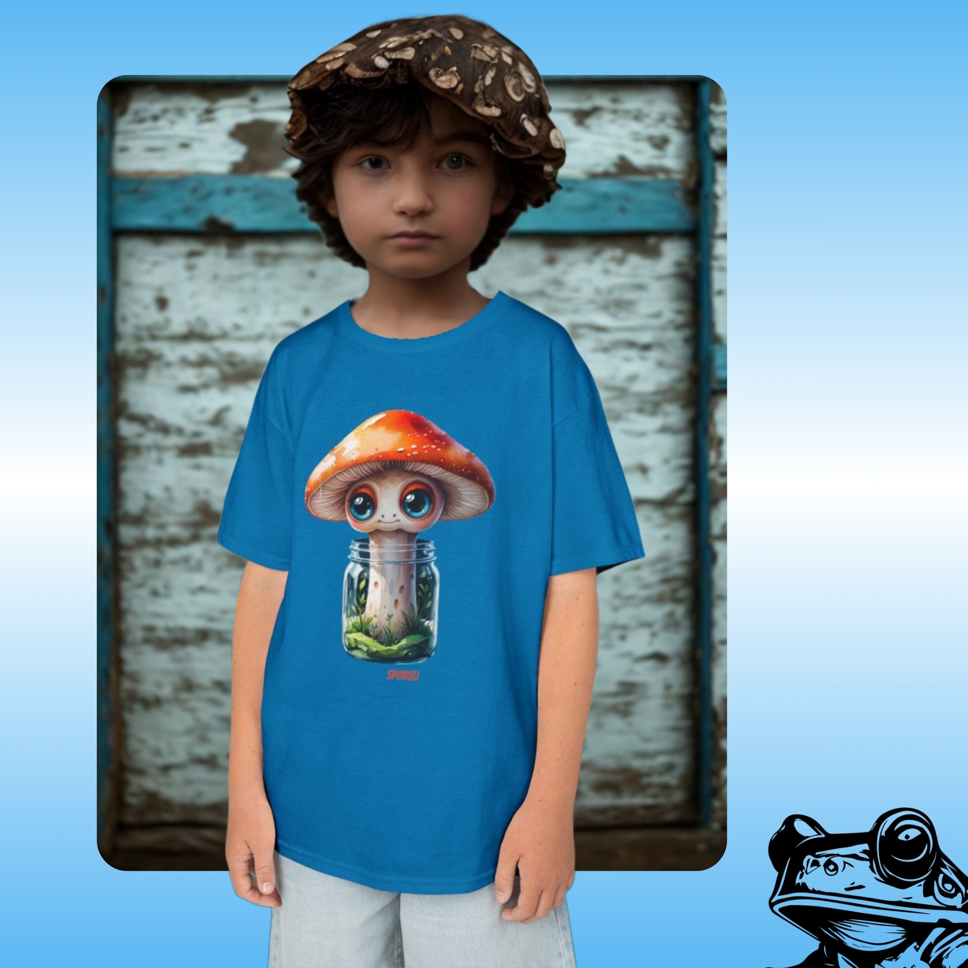Sporeli Youth Tee T-shirt in blue with a young mushroom boy wearing the mushroom in a jar unisex top | Child wearing a blue t-shirt with a cartoon mushroom design against a rustic wooden background.