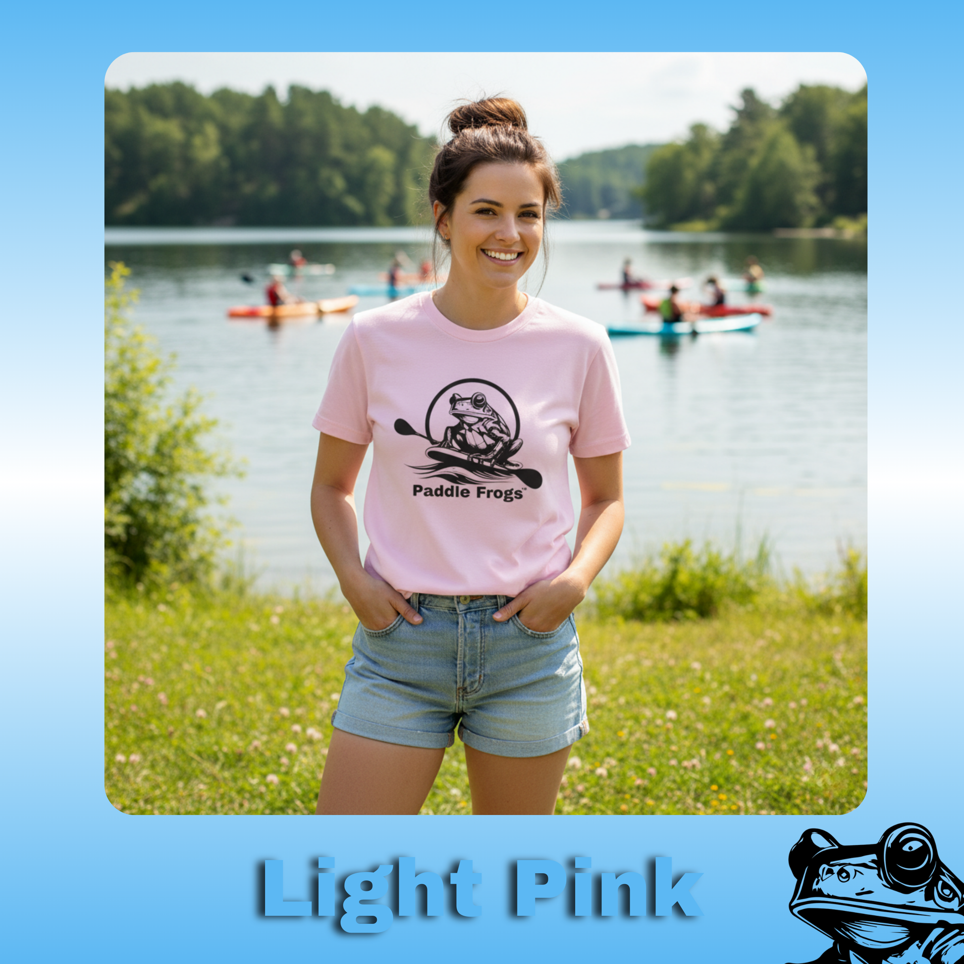 The Original Paddle Boarding T-Shirt | Paddle Frogs™ Light Pink Tee | Woman wearing a light pink t-shirt with 'Paddle Frogs' design by a lake with people kayaking.