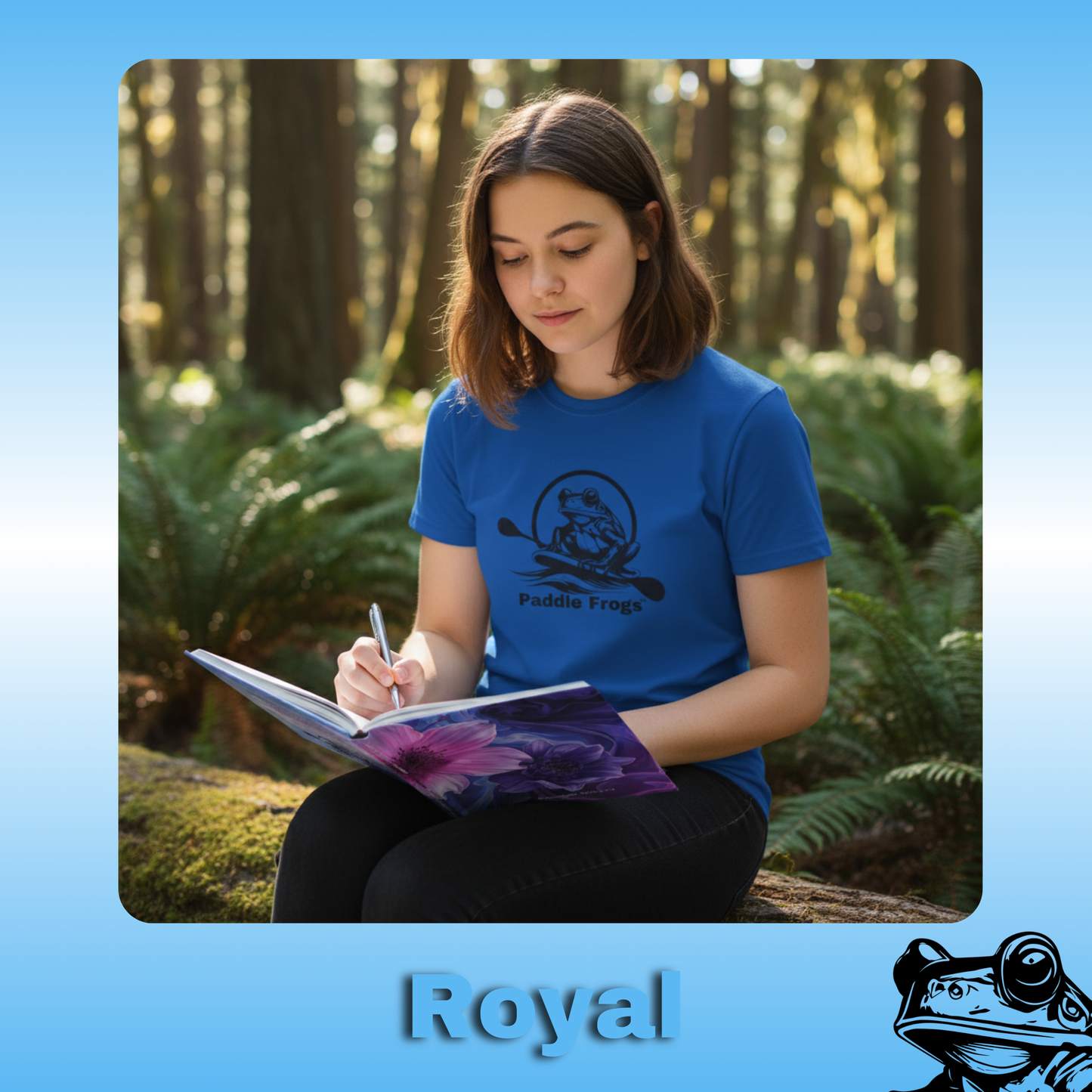 The Original Paddle Boarding T-Shirt | Paddle Frogs™ Royal (blue) Tee | Young Lady Teen Person wearing a blue shirt with a logo, sitting in a forest and writing in a notebook.