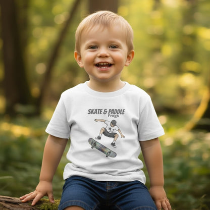 Toddler Skateboard Tee Germ "Skate & Paddle Frogs™ White in the woods with a boy sitting on a log