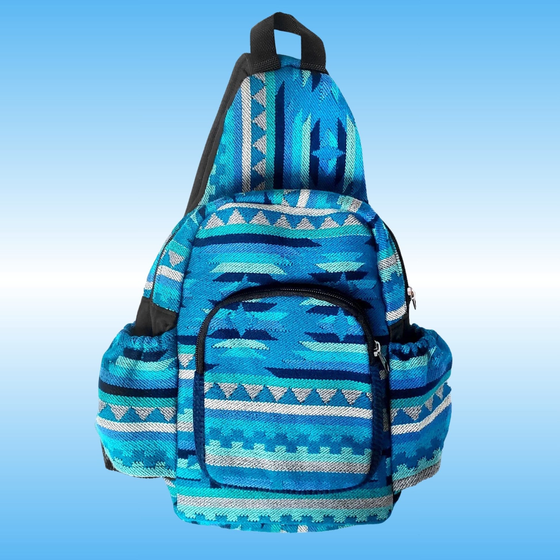 A blue patterned sling backpack with geometric Southwestern-style woven designs in shades of blue, teal, and white, featuring black straps and zippers, set against a light blue gradient background.