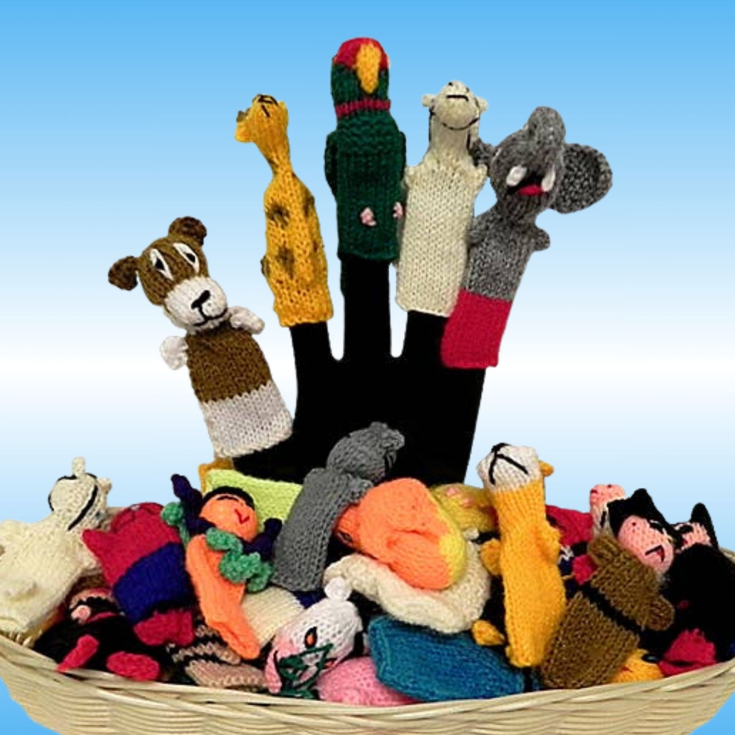 A collection of colorful hand-knitted animal and character finger puppets displayed upright on a black hand-shaped stand, with additional puppets piled in a woven basket against a light blue gradient background.