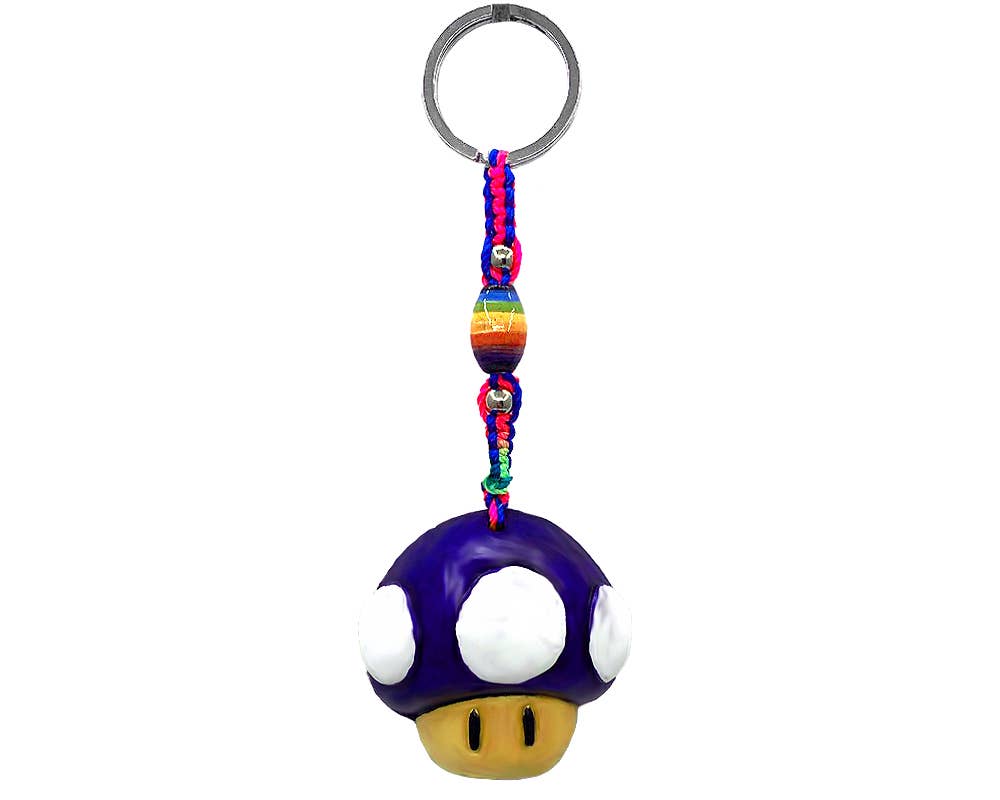 A Super Mushroom keychain featuring a purple and white mushroom charm with a yellow face, attached to a colorful braided cord with rainbow beads and a silver metal key ring, shown on a plain white background.