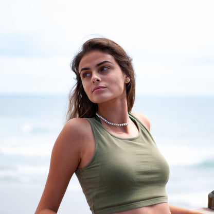 Woman wearing a hemp necklace and a green tank top with a blurred background