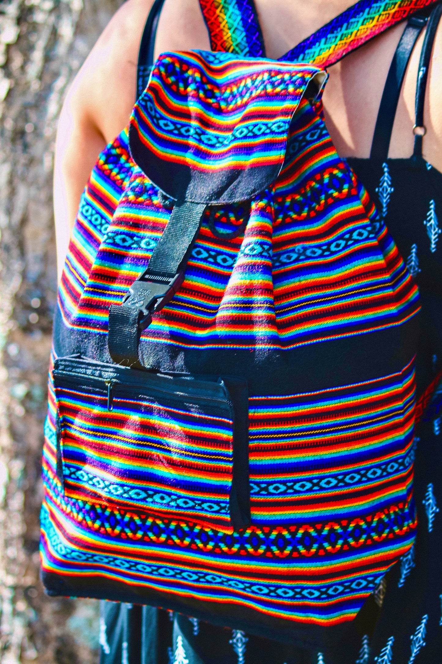 Backpack with colorful rainbow pattern worn by a person against a natural background