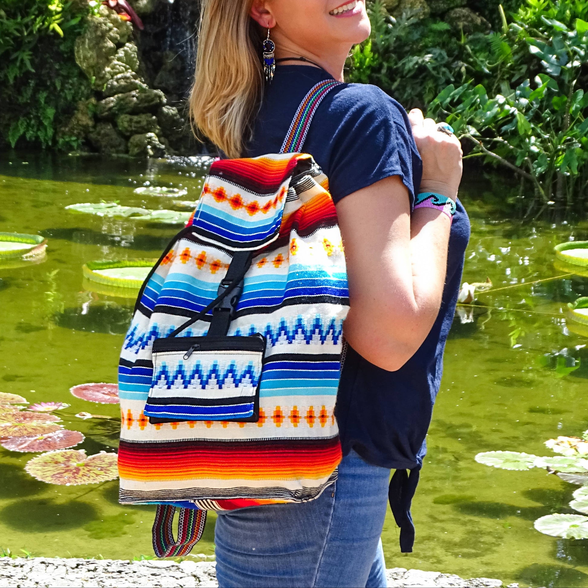 Woman with a colorful backpack standing by a pond with lily pads