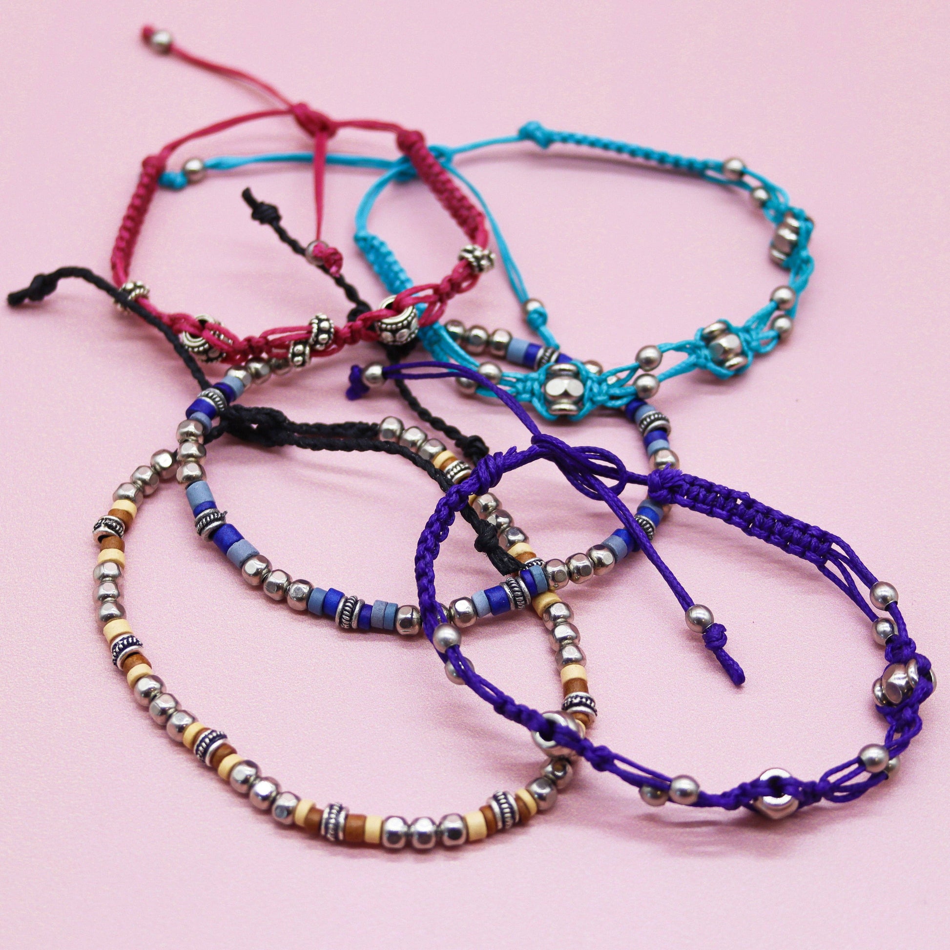 Colorful beaded bracelets on a pink background