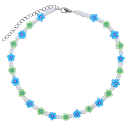 A beaded necklace featuring alternating white cylindrical beads and small flower charms in blue, green, and pink, with a silver-tone chain extender and clasp.