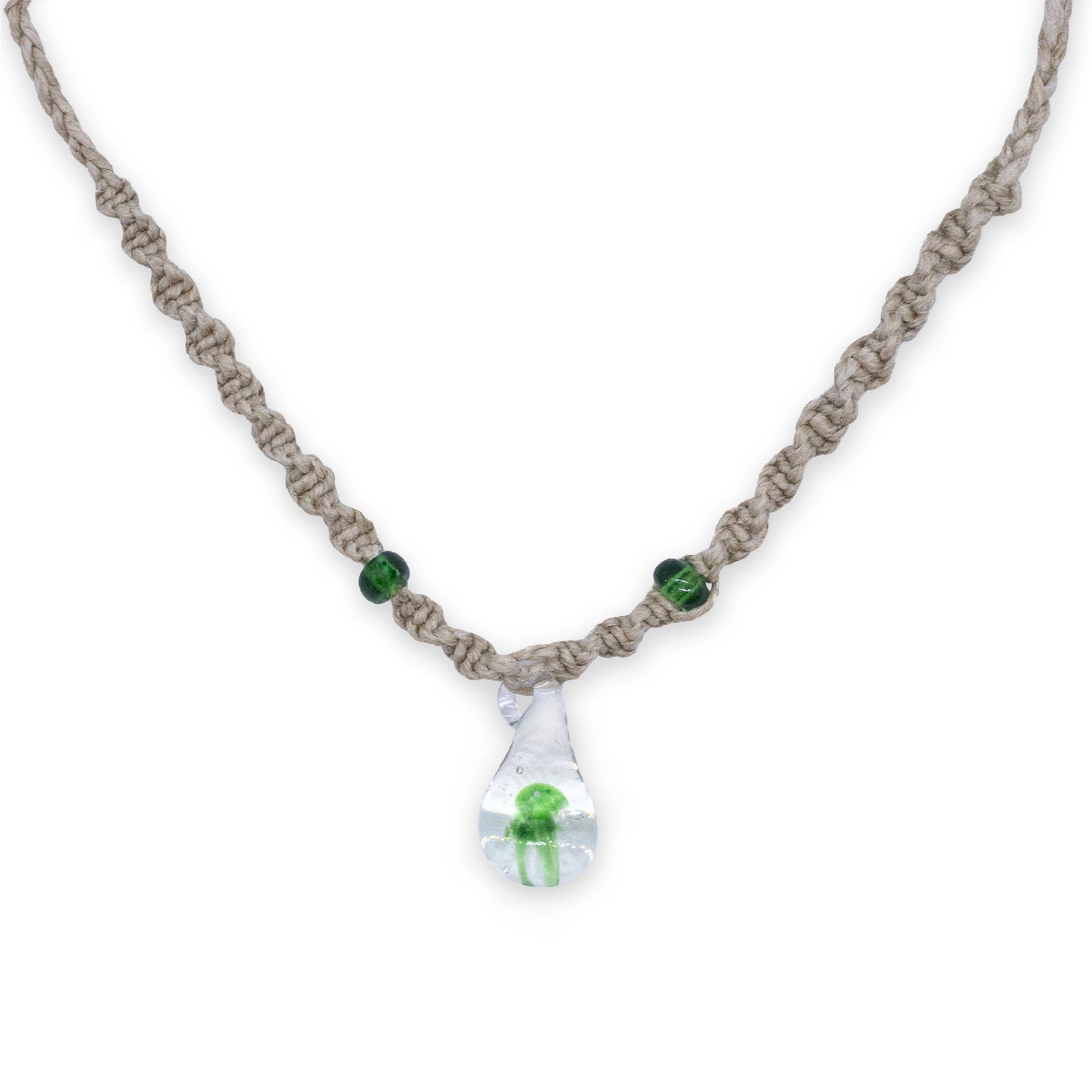 A handmade macrame necklace with a clear teardrop pendant containing a small green mushroom frog, accented with two green beads on a white background.