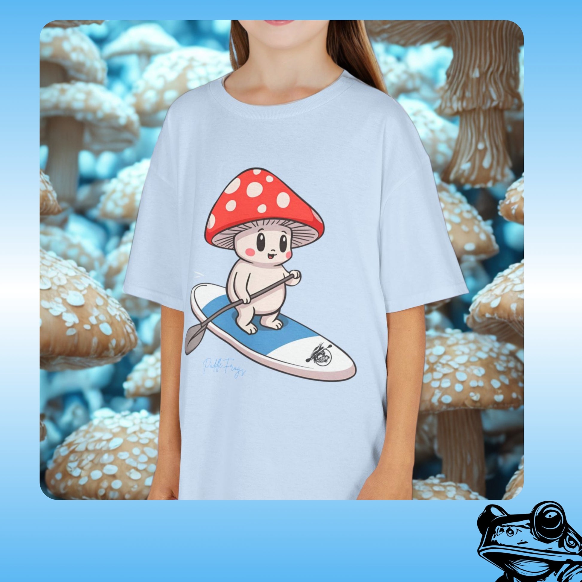 mushroom creature riding the Divine Escape paddle board kids blue T-Shirt by Paddle Frogs | Person wearing a t-shirt with a cartoon character on a mushroom and paddle design, set against a mushroom-themed background.