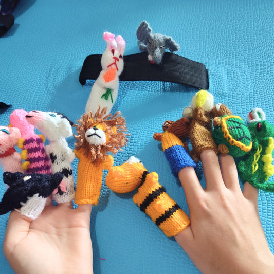 Handmade finger puppets on a person's fingers against a blue background