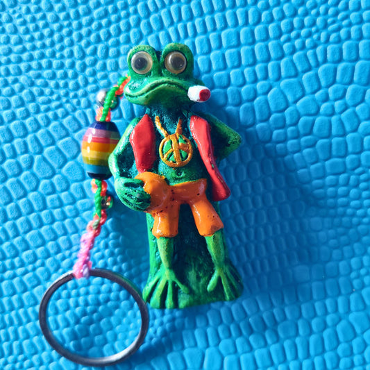 Colorful frog figurine keychain with peace sign on a blue textured background