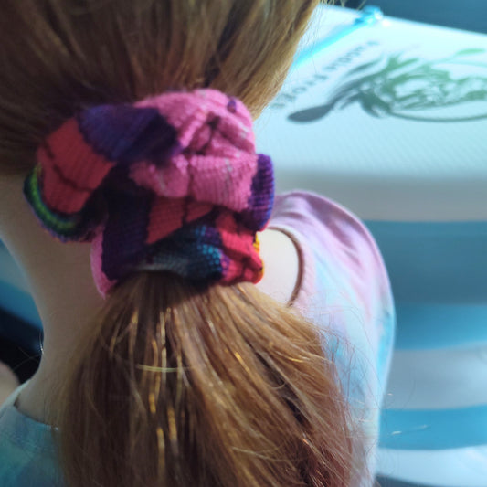 Close-up of a colorful scrunchie on a person's hair with a blurred background