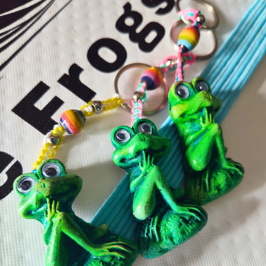 Green frog-shaped keychains with colorful beads on a white background with 'Frogs' text.
