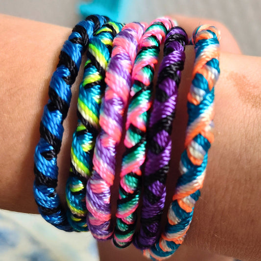 Colorful braided BFF friendship bracelets on a wrist against a neutral background