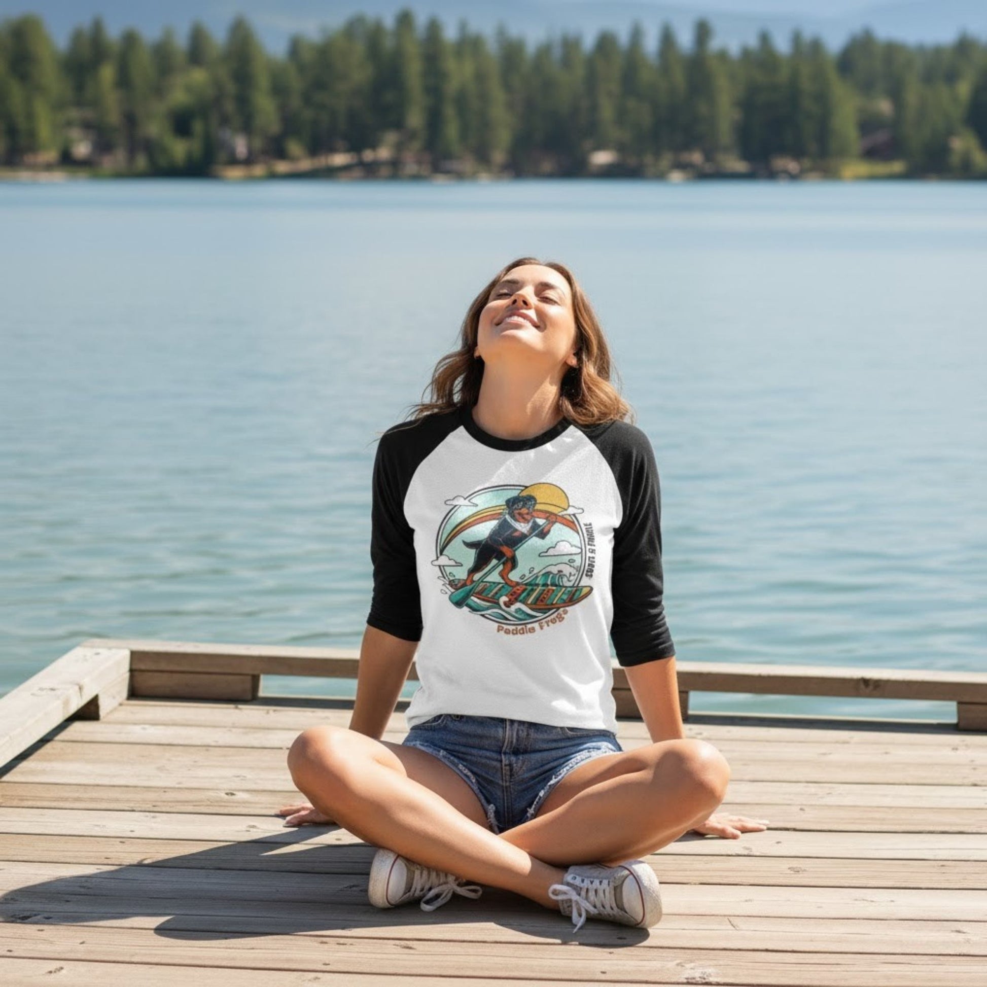 sitting crisscross applesauce at the lake wearing a Rottweiler Paddleboarding tee by Paddle Frogs