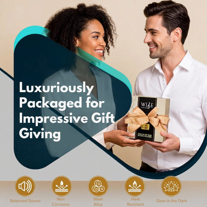 A man in a white shirt and a woman in a gray blazer are smiling while presenting a boxed gift. The gift box is wrapped in beige ribbon and labeled WISE steel tongue drum.