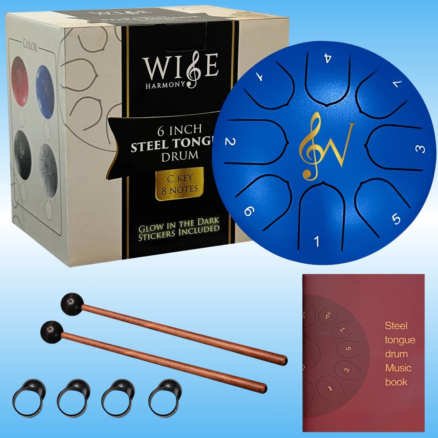 A steel tongue drum set shown with its retail box, a blue circular drum head, two copper-colored mallets with black tips, four black ear-cuff style accessories, and a small music book on a light blue gradient background. The box reads 'Wise Harmony 6 Inch Steel Tongue Drum' and the drum has gold logo and white glow in the dark note numbers.